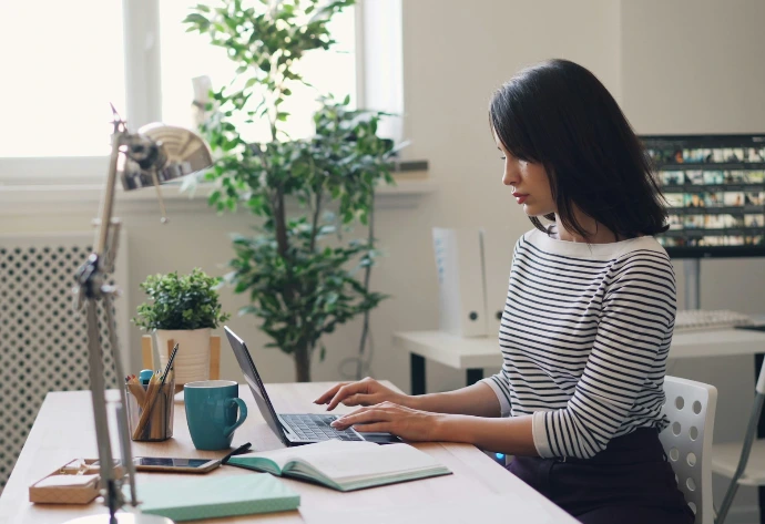 a woman sitting at a desk using a laptop computer